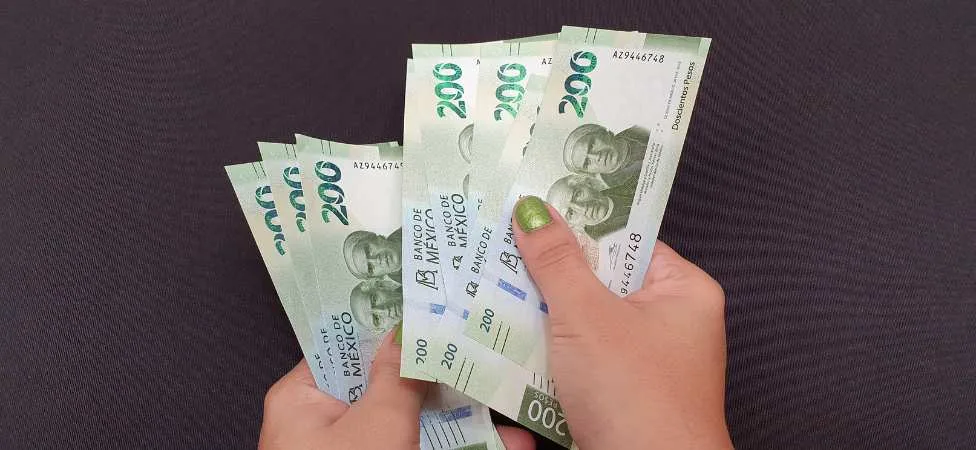 manos sosteniendo billetes mexicanos