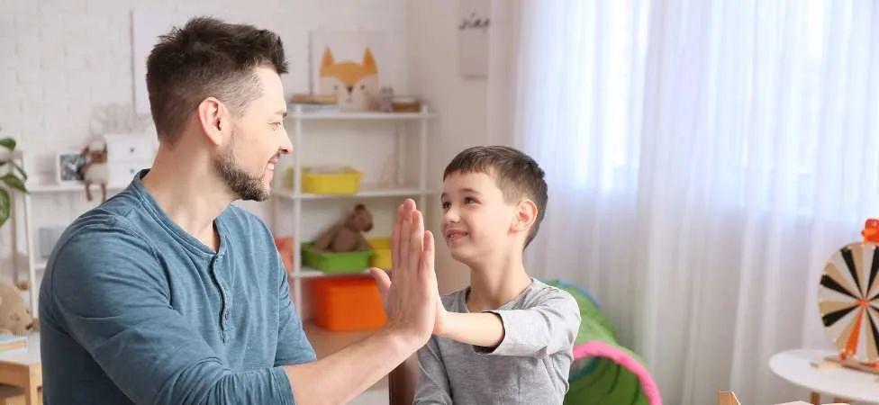 trabajador social chocando su palma con un niño