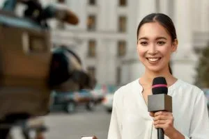 estudiar periodismo en estados unidos: mujer frente a cámara con un micrófono